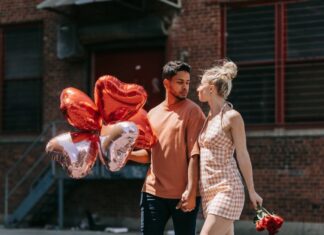 Poljubi i reci woman in red sleeveless dress holding red heart shaped balloons
