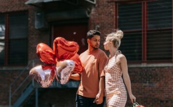 Poljubi i reci woman in red sleeveless dress holding red heart shaped balloons
