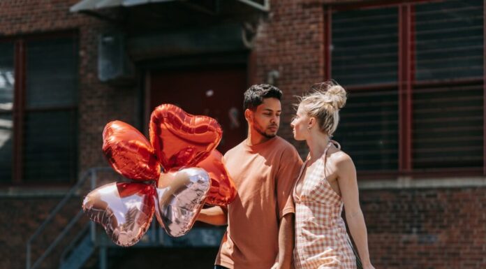 Poljubi i reci woman in red sleeveless dress holding red heart shaped balloons