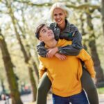 Funny couple in a urban park. Boyfriend carrying his girlfriend on piggyback.