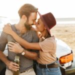 Loving couple outdoors at beach near car.