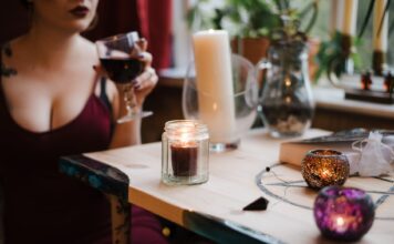 Tajanstvena žena unrecognizable soothsayer with glass of drink at table