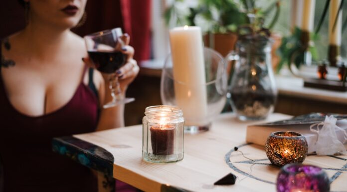 Tajanstvena žena unrecognizable soothsayer with glass of drink at table