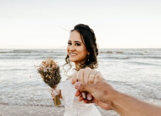 Neobična prosidba bride in white dress standing on sandy beach