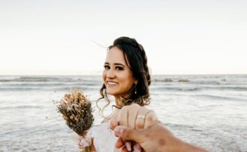 Neobična prosidba bride in white dress standing on sandy beach