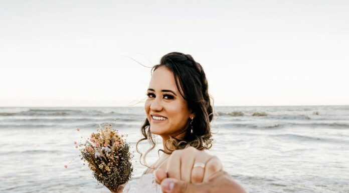 Neobična prosidba bride in white dress standing on sandy beach