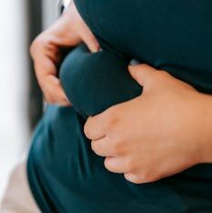 VEČERAS PRIJE SPAVANJA POPIJTE OVAJ NAPITAK I MRŠAVITE U SNU: Više se nećete mučiti s viškom masnih naslaga na bokovim i stomaku Unrecognizable plus size female in activewear touching folds on belly while standing on blurred background during training in light gym
