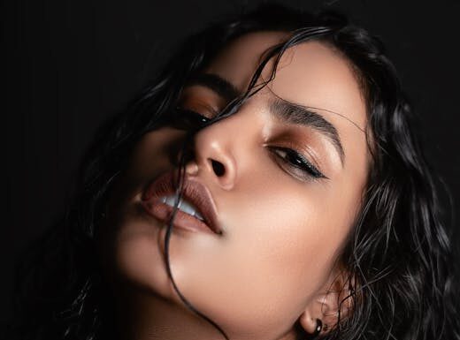Ucenjena Striking portrait of a woman with wet hair and intense gaze, captured in a studio setting.